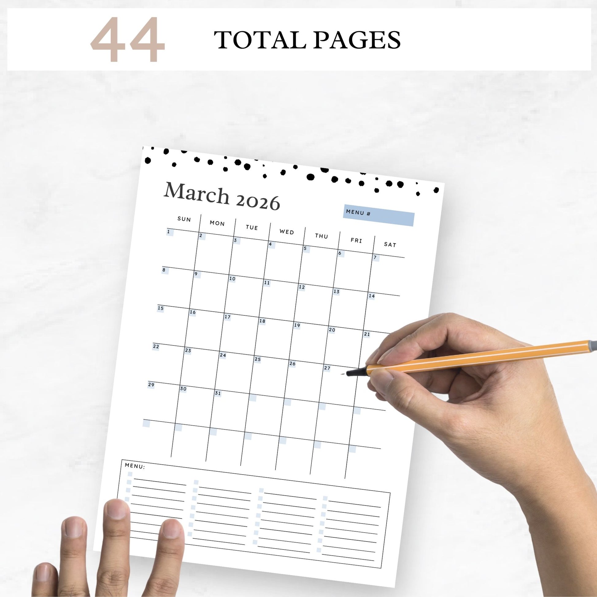 text on image reads "44 total pages." Hand holding a pencil shown hovering above the printable monthly calendar page on a white marble background.